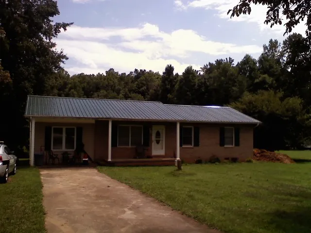 Dark green metal roof on a brick ranch with a covered porch in Spring Hill