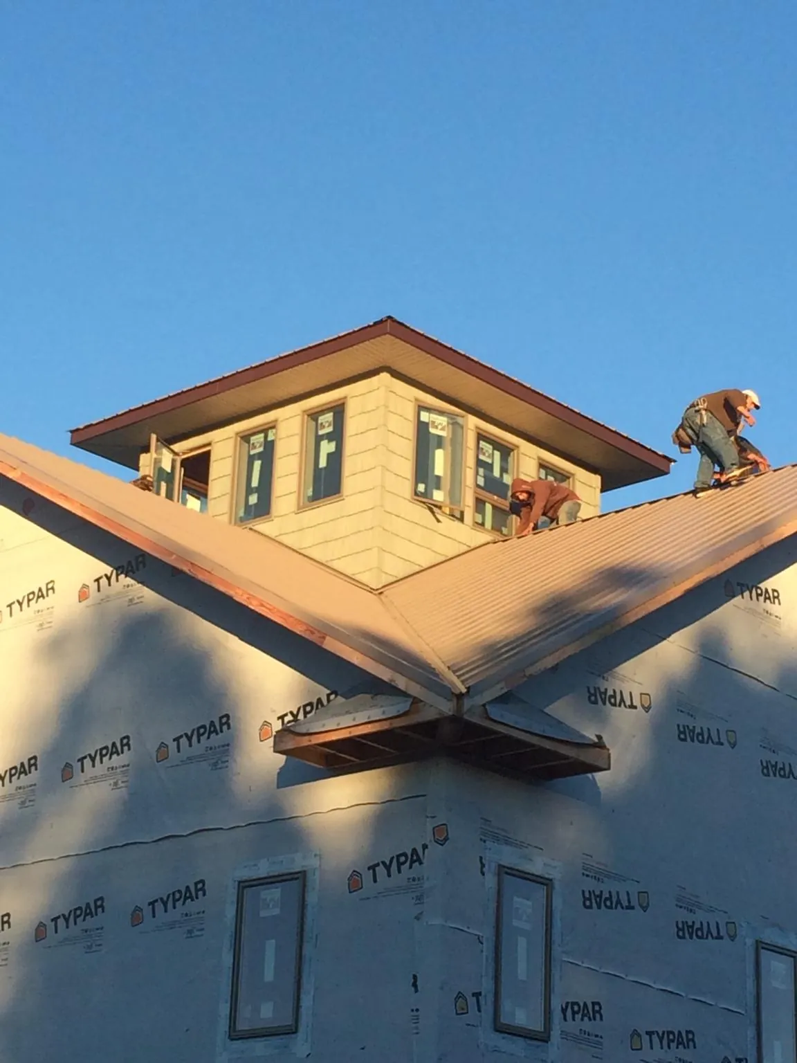 Roofers working around a rooftop cupola on a new metal roof at sunset — Roof Waterproofing in Spring Hill by Roofing Brothers